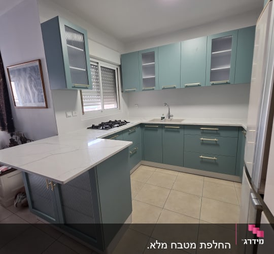 מטבח מודרני עם ארונות כחולים ומשטח עבודה לבן